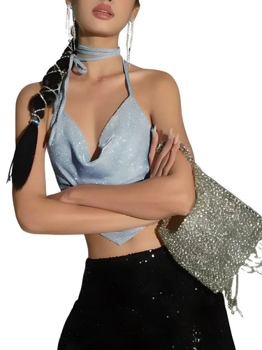 Woman wearing a sparkly blue halter top and black pants with a matching bag on a white background